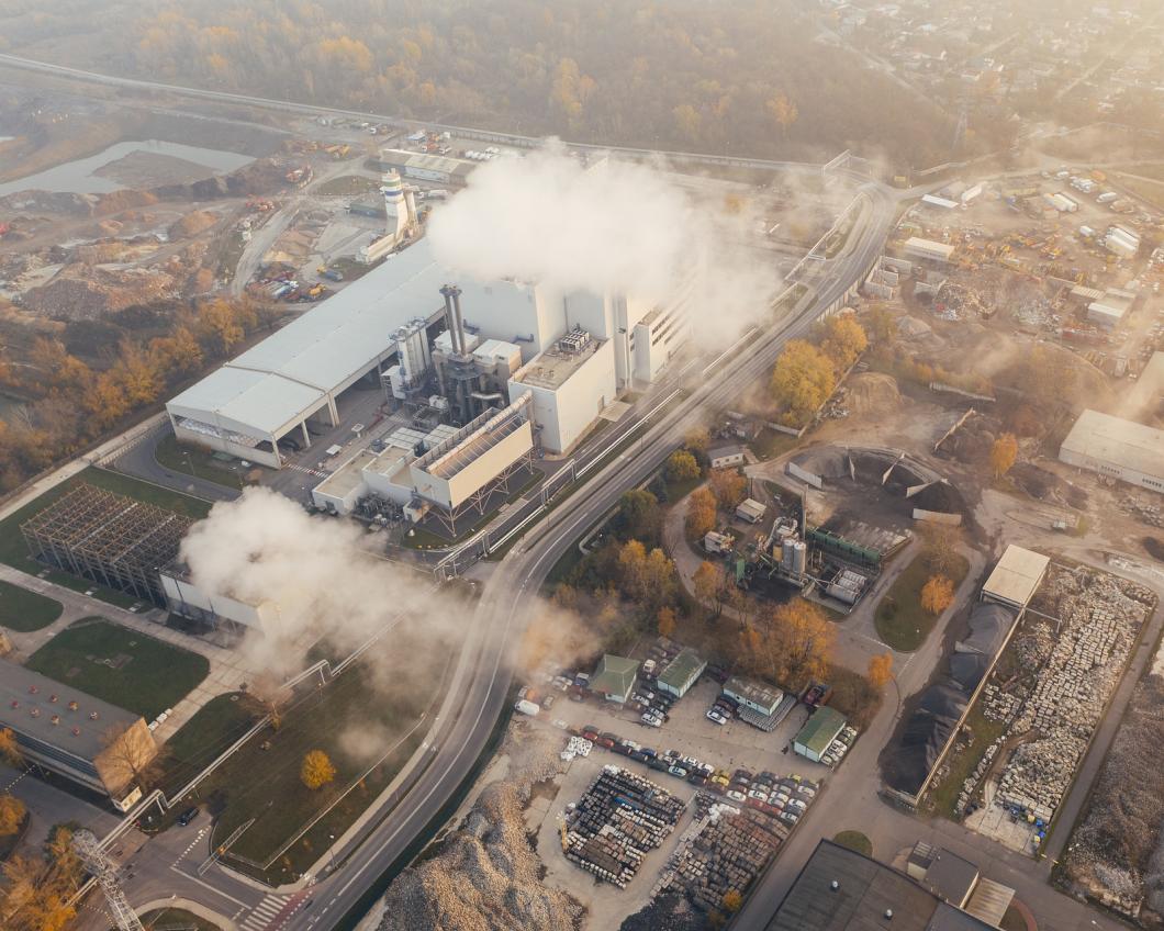 Een fabriek stoot grote witte rookpluimen uit