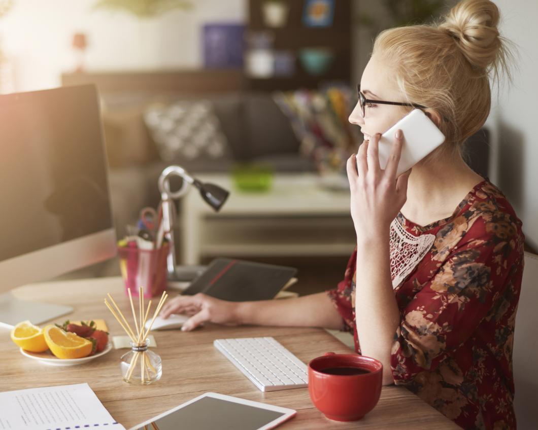 Een vrouw zit bellend achter haal laptop